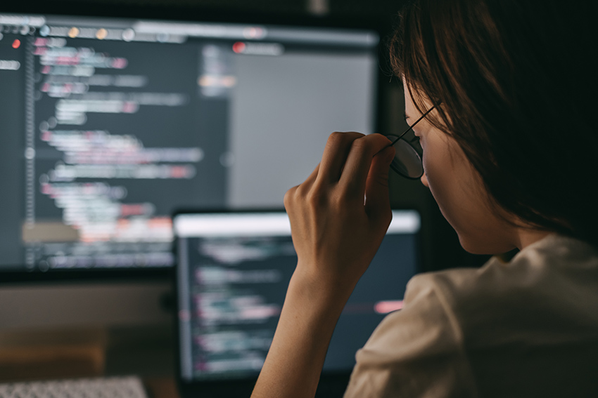 Young caucasian female programmer in glasses writes program code