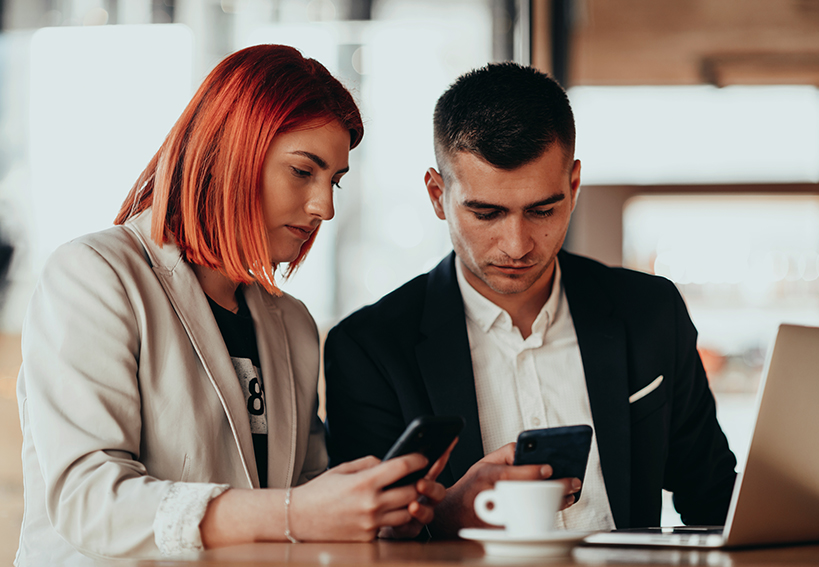 Man and woman using computer and phones